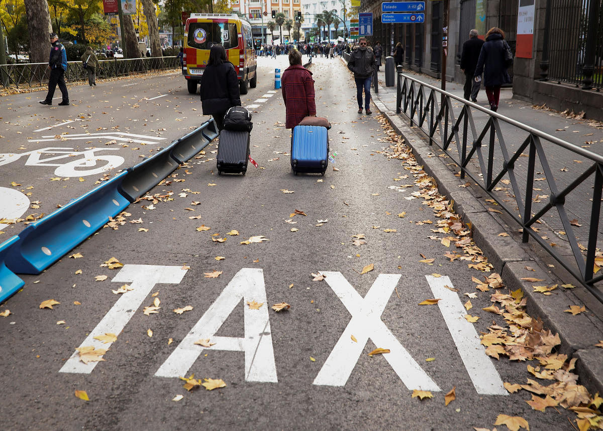 People walk down a taxi lane during a strike by taxi drivers to protest what they say is unfair competition from new car sharing companies such as Uber and Cabify, in Madrid, Spain, November 29, 2017. REUTERS/Sergio Perez