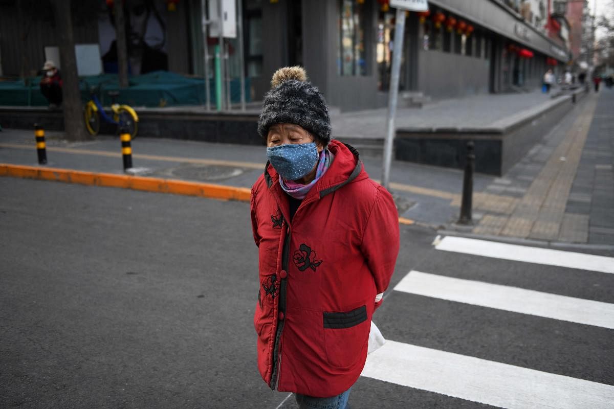 A woman wears a mask as a preventive measure against the COVID-19 coronavirus as she crosses a road in Beijing on March 9, 2020. Credit: AFP Photo