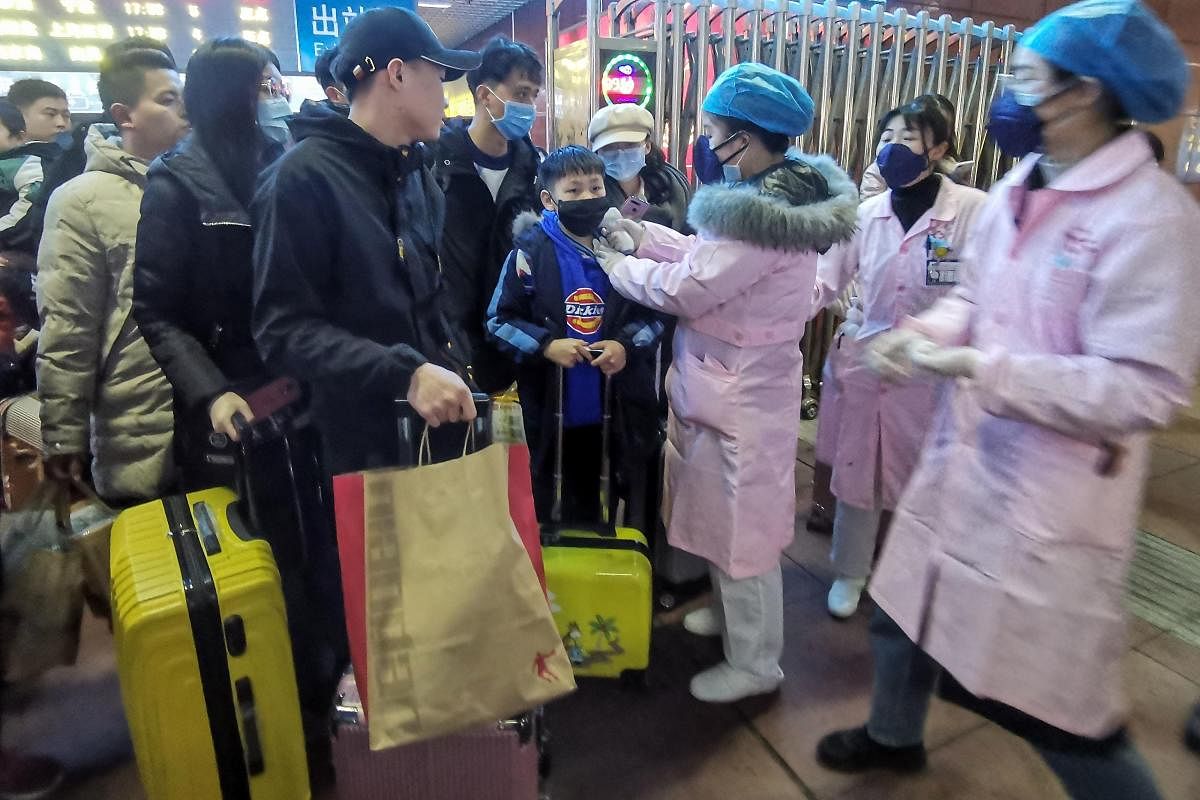This photo taken on January 22, 2020 shows a staff member (center R) checking body temperature of a passenger at the Yingtan North Railway Station in Nanchang in China's central Jiangxi province. AFP photo for representation