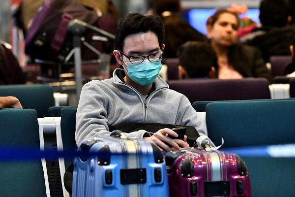 A traveller wearing a mask, sits at Vancouver International Airport (YVR) as Canada's Public Health Agency added a screening question for visitors and began displaying messages in several airports urging travellers to report flu-like symptoms in efforts to prevent any introduction of coronavirus, in Richmond, British Columbia, Canada January 24, 2020. (Reuters Photo)