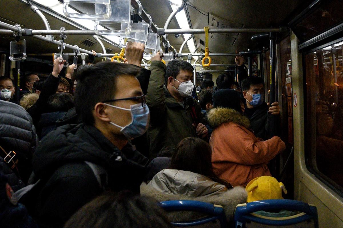 Passengers wearing protective face masks look on aboard a shuttle bus at the Shanghai Pudong International Airport in Shanghai on February 4, 2020. Credit: AFP Photo