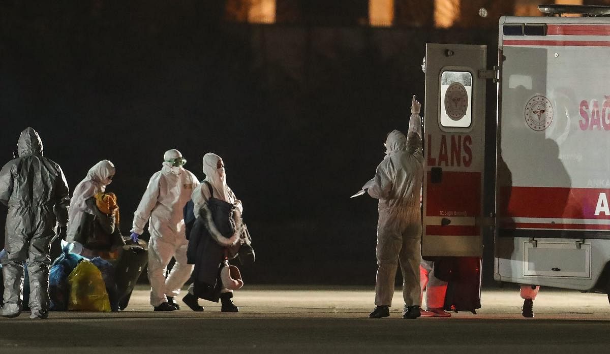 Passengers grab their luggages as they disembark a Turkish cargo plane before entering an ambulance at the Etimesgut military Airport in Ankara on February 1, 2020, after being repatriated from the Chinese city of Wuhan, the epicentre of the new coronavirus outbreak. (AFP Photo)