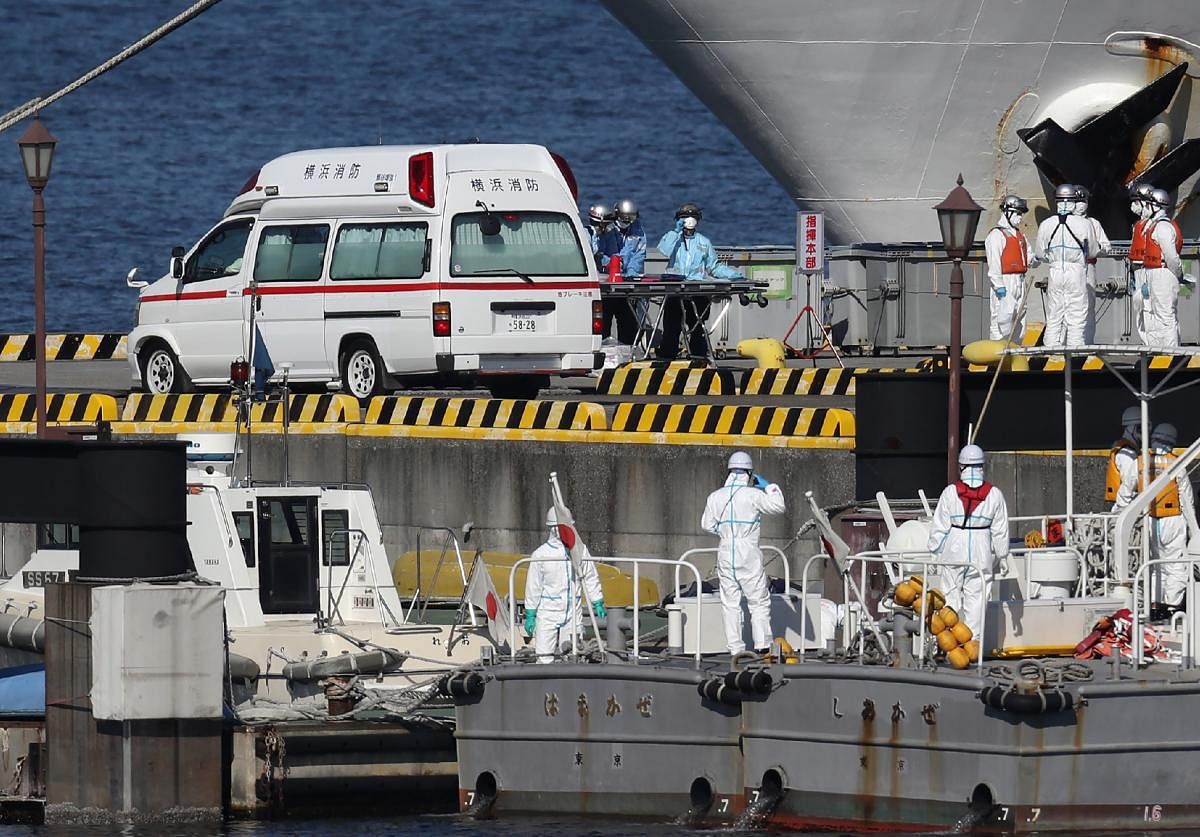 Workers in protective gear are seen next to a waiting ambulance at the Japan Coast Guard base in Yokohama on February 5, 2020, to bring the patients from the Diamond Princess cruise ship which remains offshore at the port. Credit: AFP Photo