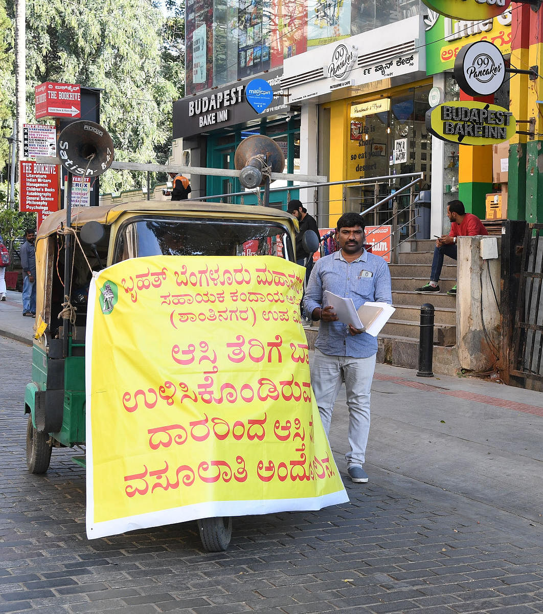 Armed with loudspeakers, BBMP officials set out to issue notices to property tax defaulters. DH PHOTO/Srikanta Sharma R