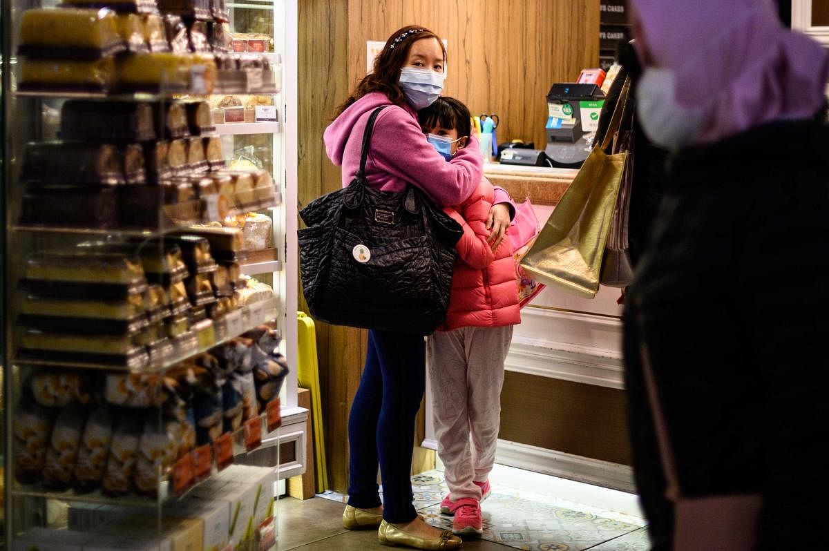 People wearing face masks inside a bakery react as residents in Mei Foo district protest against government plans to convert the Jao Tsung-I Academy a local heritage site into a quarantine camp amid the outbreak of the novel coronavirus which began in the
