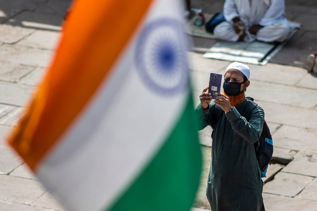 A man, wearing a facemask amid concerns over the spread of the COVID-19 novel coronavirus, takes pictures with a mobile phone at the Jama Masjid mosque in the old quarters of New Delhi. (Photo by AFP)