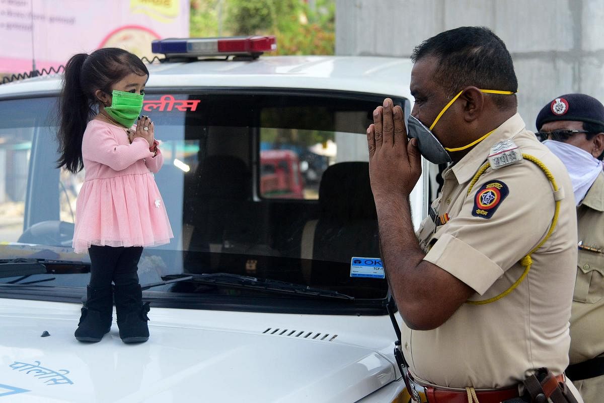 World's shortest woman Jyoti Amge greets a police personnel, both wearing masks, during an awareness campaign about COVID-19, in Nagpur, Monday, April 13, 2020. (PTI Photo)