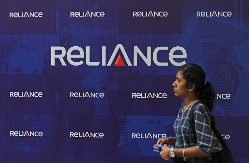 A woman walks past the logos of Reliance Anil Dhirubhai Ambani Group during the company's annual general meeting in Mumbai, India. (PTI Photo)