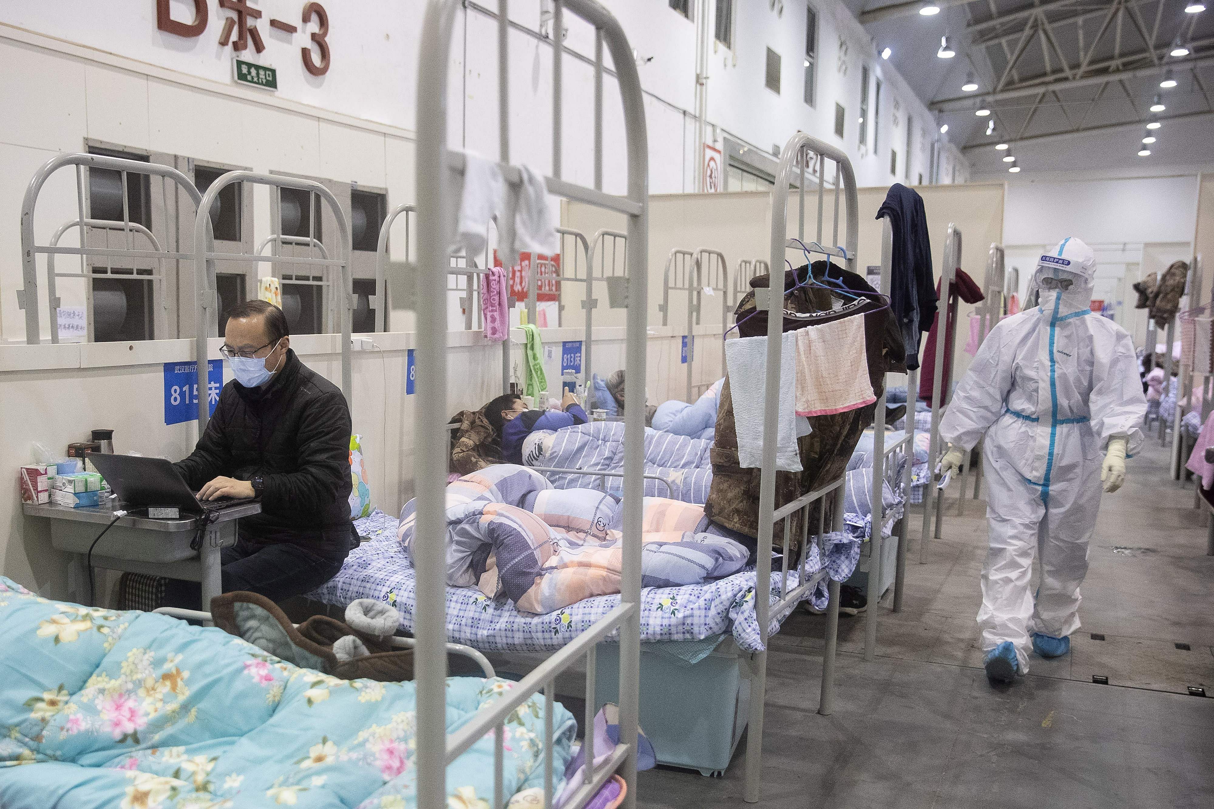 A man who has displayed mild symptoms of the COVID-19 coronavirus using a laptop at an exhibition centre converted into a hospital in Wuhan in China's central Hubei province. (Credit: AFP Photo)