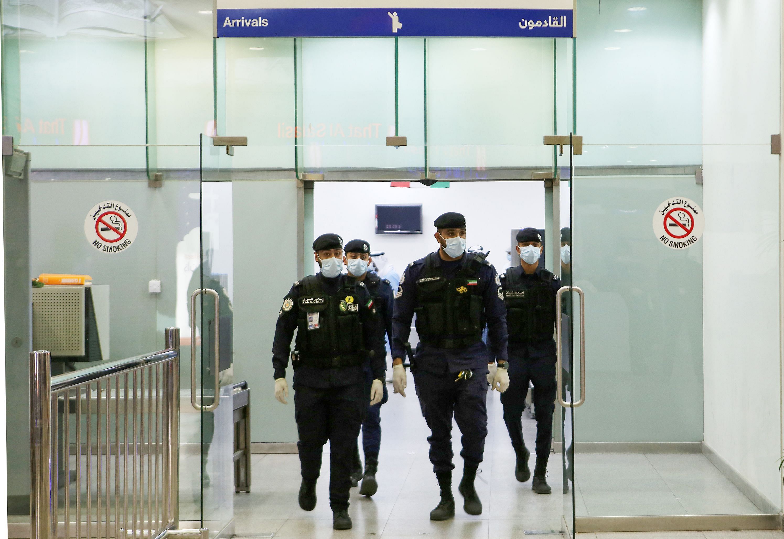 Kuwaiti policemen wearing protective masks wait at Sheikh Saad Airport in Kuwait City, on February 22, 2020, before transferring Kuwaitis arriving from Iran to a hospital to be tested for coronavirus. (Credit: AFP Photo)