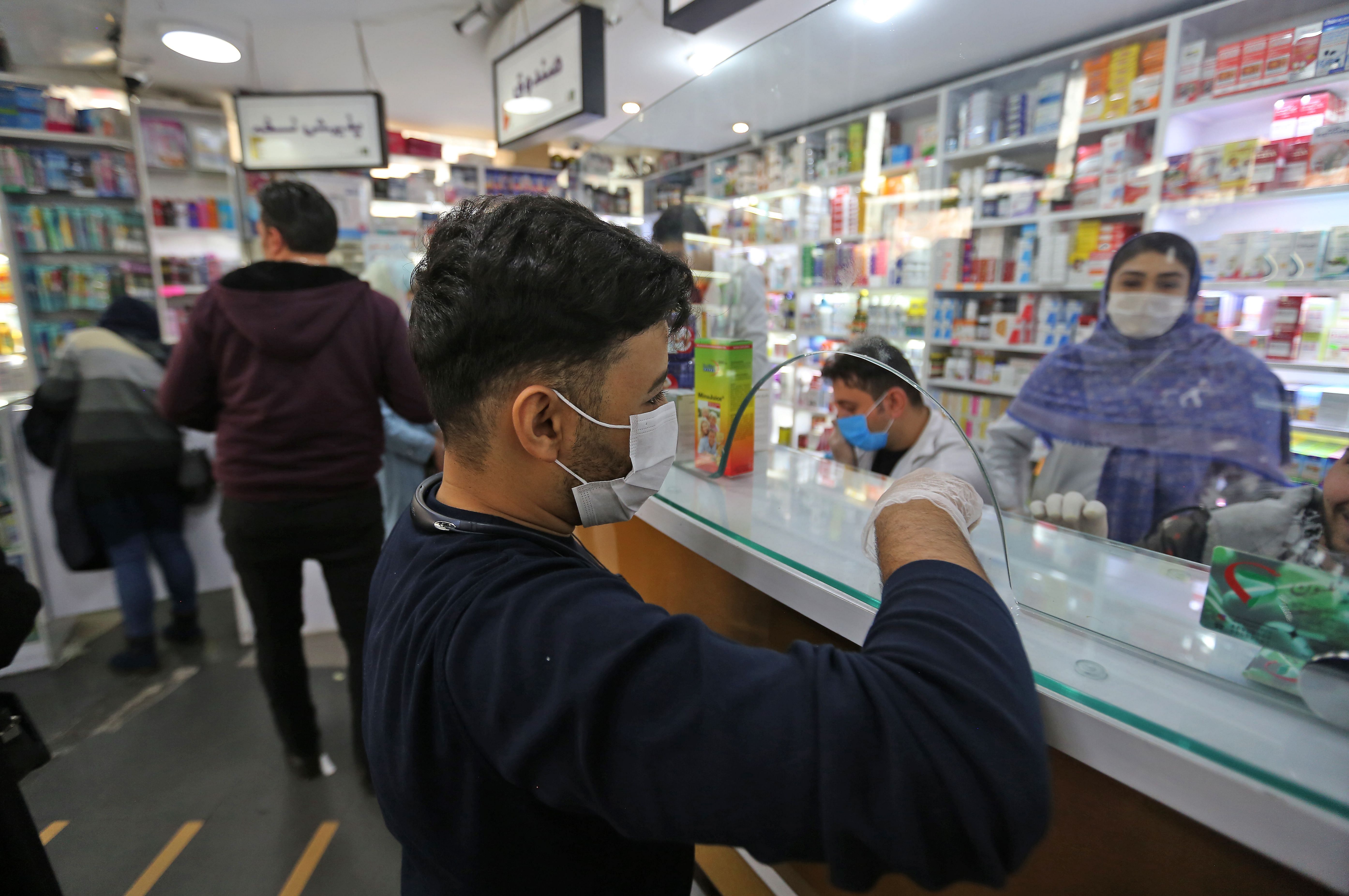People wearing protective masks shop at a pharmacy in the Iranian capital Tehran on February 24, 2020. (Credit: AFP Photo)
