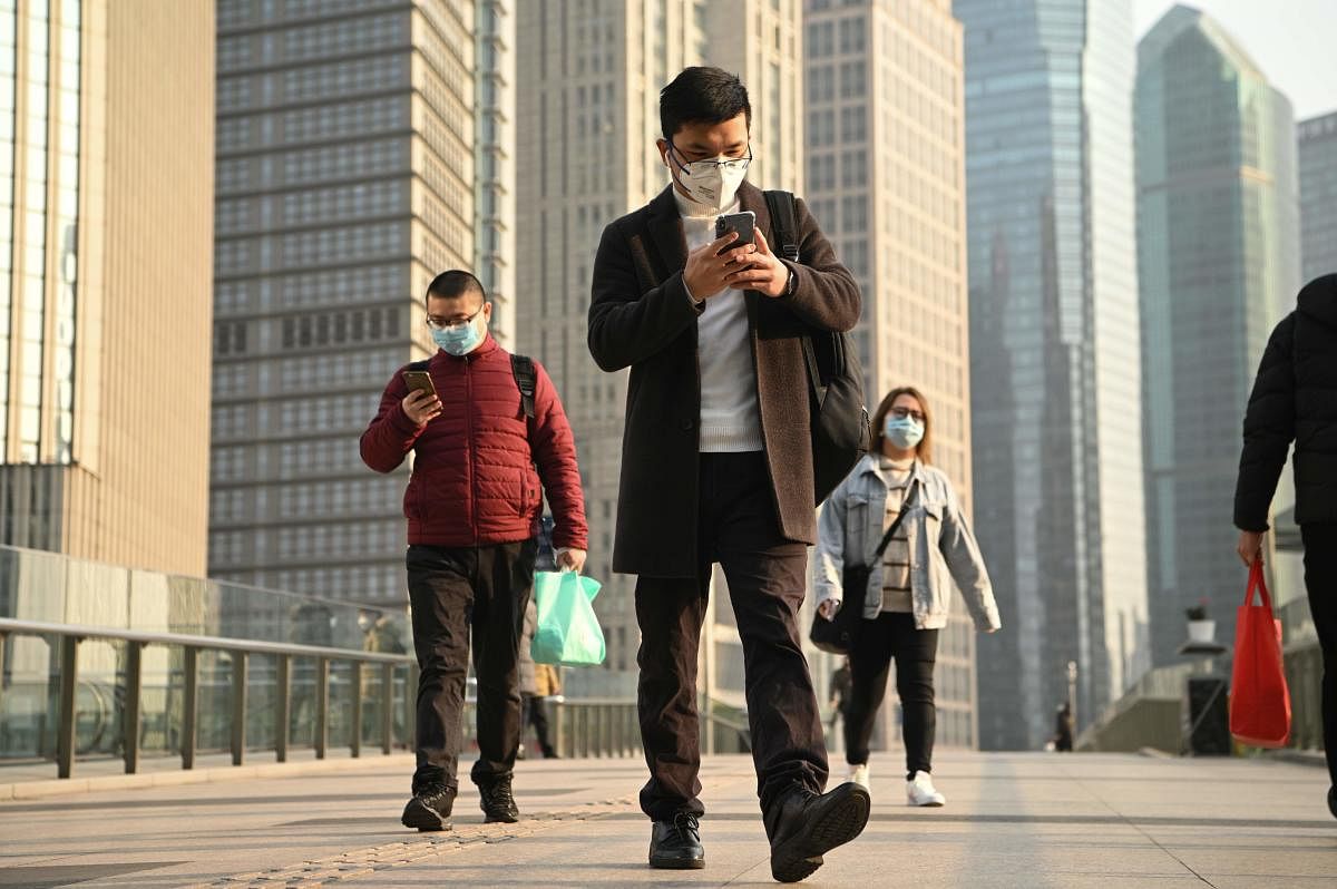 People wearing protective face masks walk on an overpass in Shanghai. (AFP Photo)