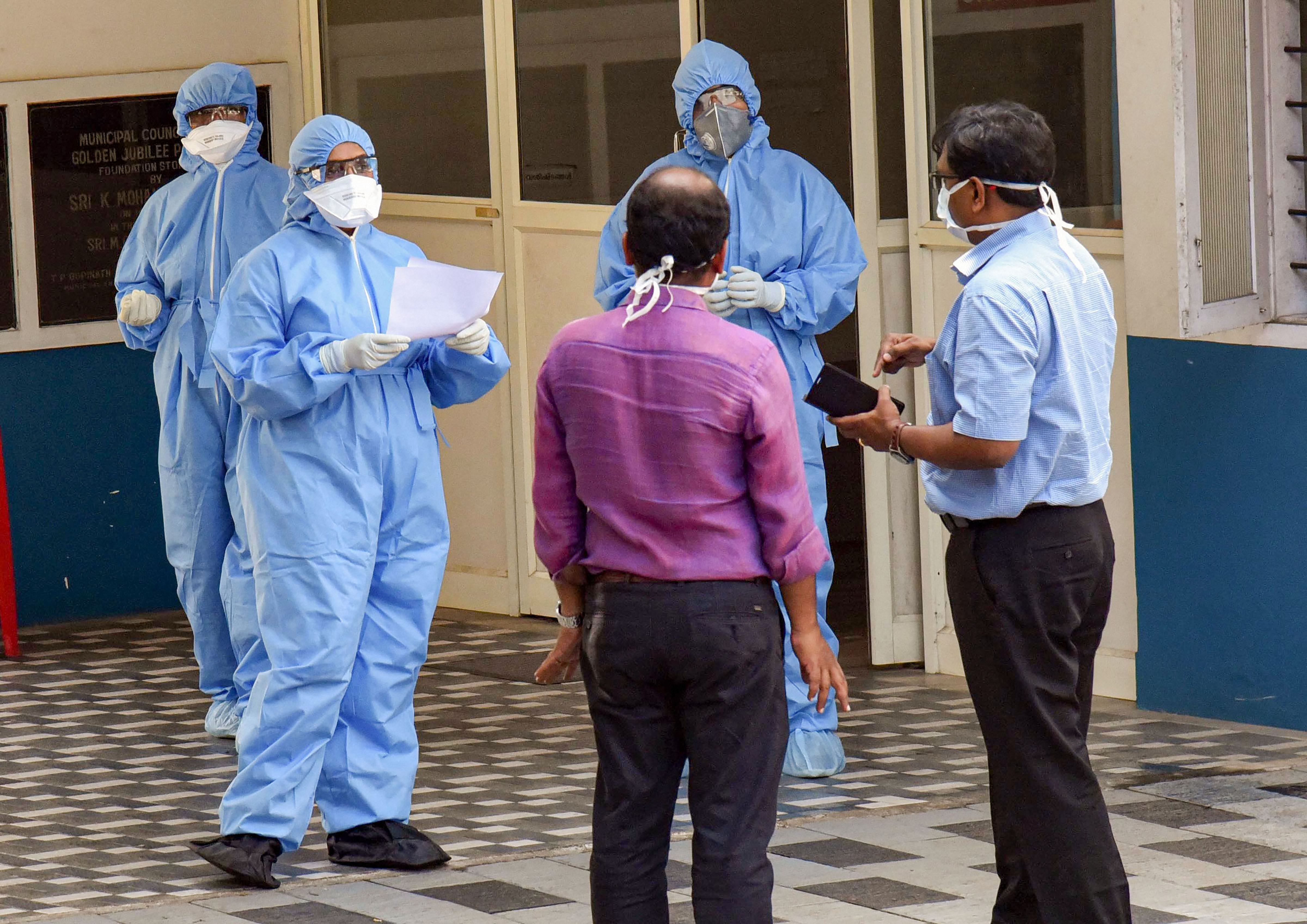 Medics wearing protective suits interact with each other outside an isolation ward, set up in view of coronavirus pandemic. (PTI Photo)
