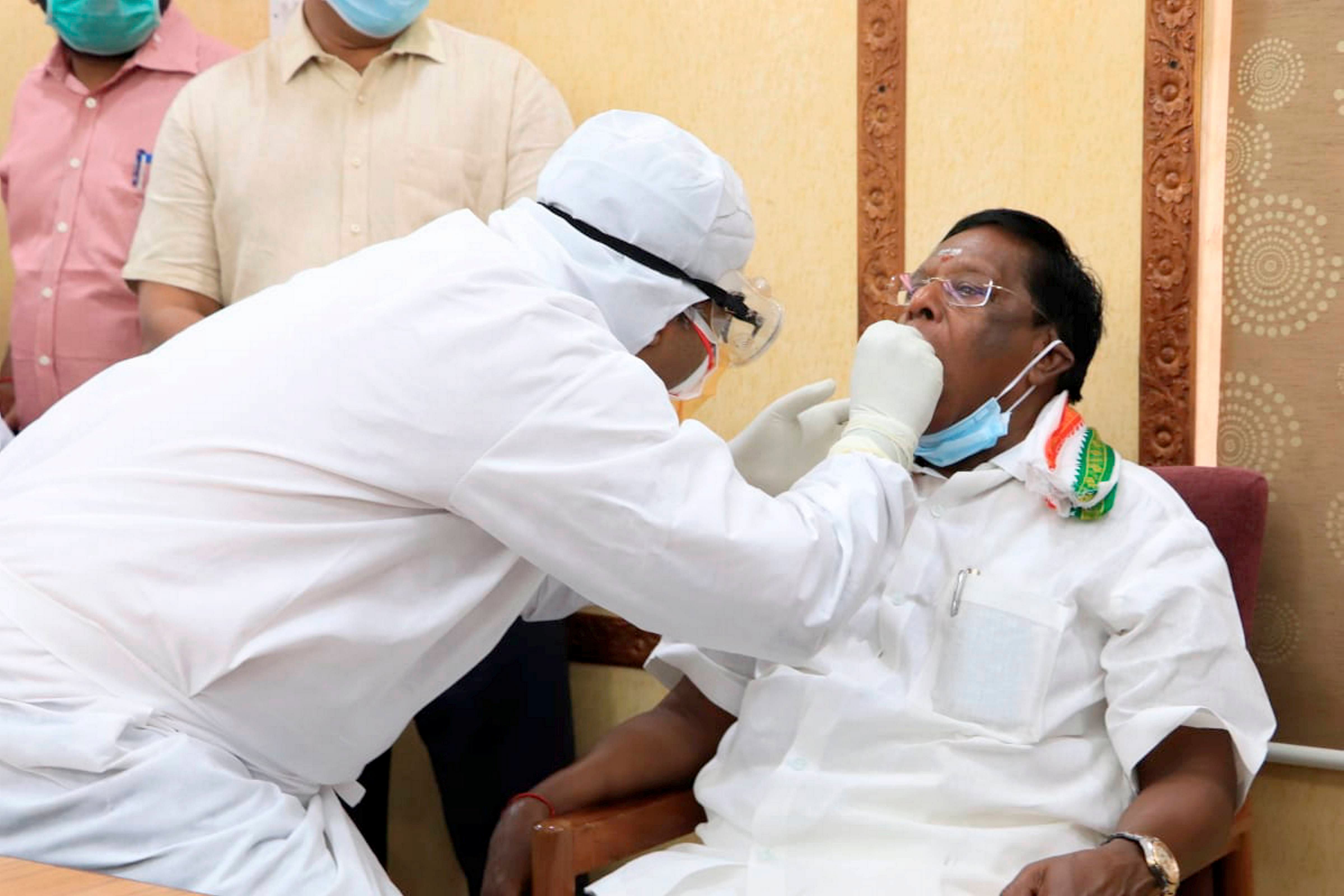 Puducherry Chief Minister V Narayanasamy gives swab sample to a medic for COVID-19 test. (Credit: PTI Photo)