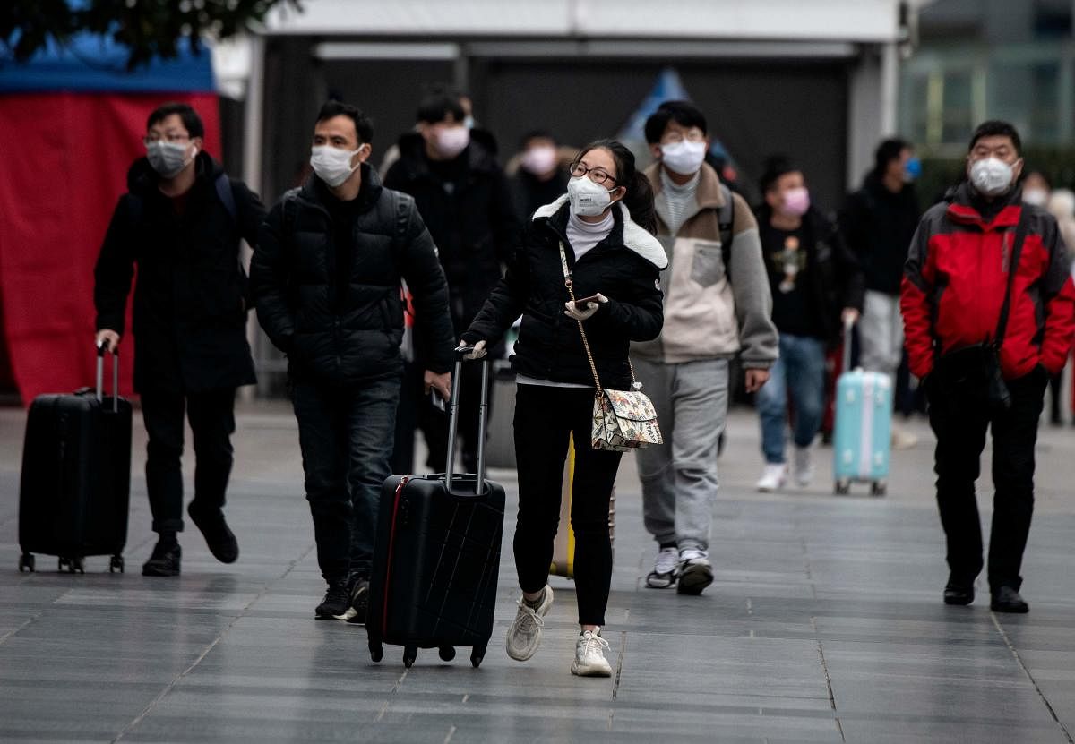 People wearing protective face masks arrive at a railway station in Shanghai. AFP