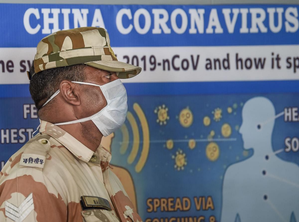  A security wearing a protective mask stands guard as Indians who were air-lifted from Wuhan following outbreak of the deadly novel coronavirus, prepare to leave following their release from the ITBP quarantine facility, at Chhawla, in New Delhi, Monday, Feb 17,2020. Credit: PTI Photo