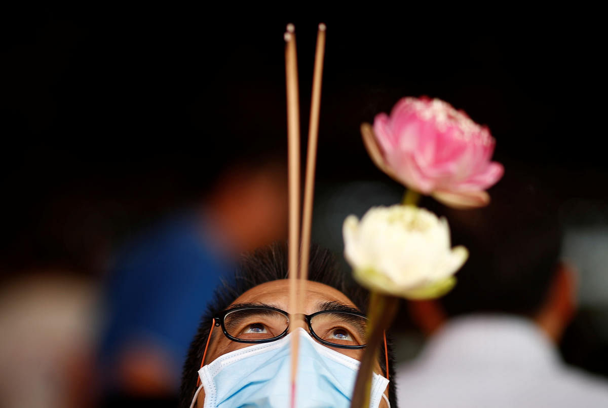 A man wearing a mask in precaution of the coronavirus outbreak prays at the Kwan Im Hood Cho Temple in Singapore. Reuters