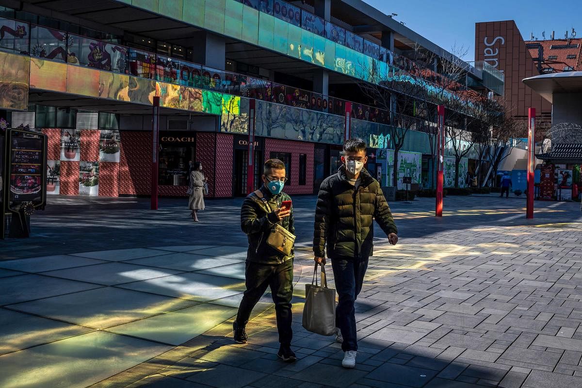 People wearing protective facemasks walk outside a nearly empty shopping mall at lunch time in Beijing on February 22, 2020. Credit: Reuters Photo