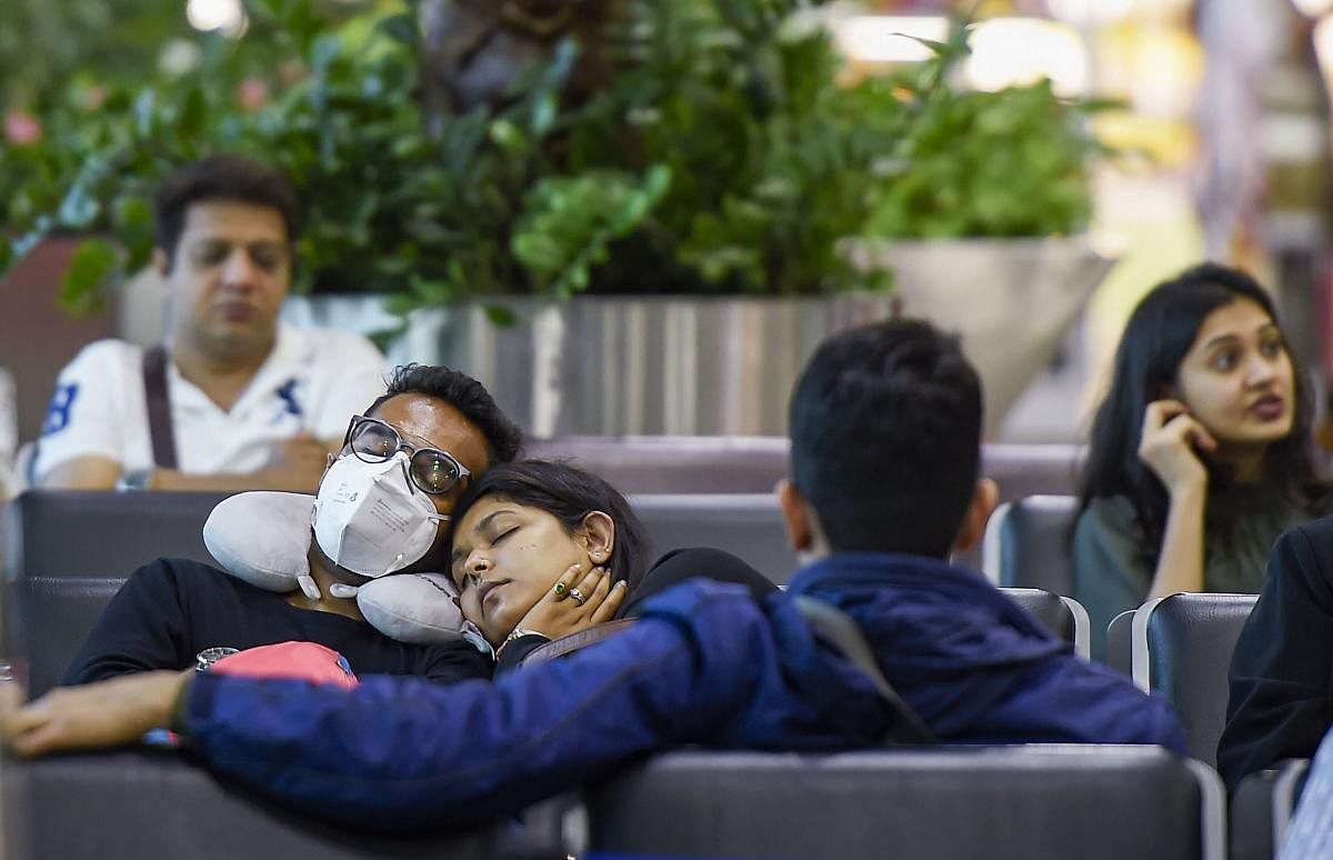  A man wearing a mask as part of preventive measures for the deadly coronavirus, takes a nap at an airport in Mumbai, Saturday, Feb. 22, 2020. Credit: PTI Photo