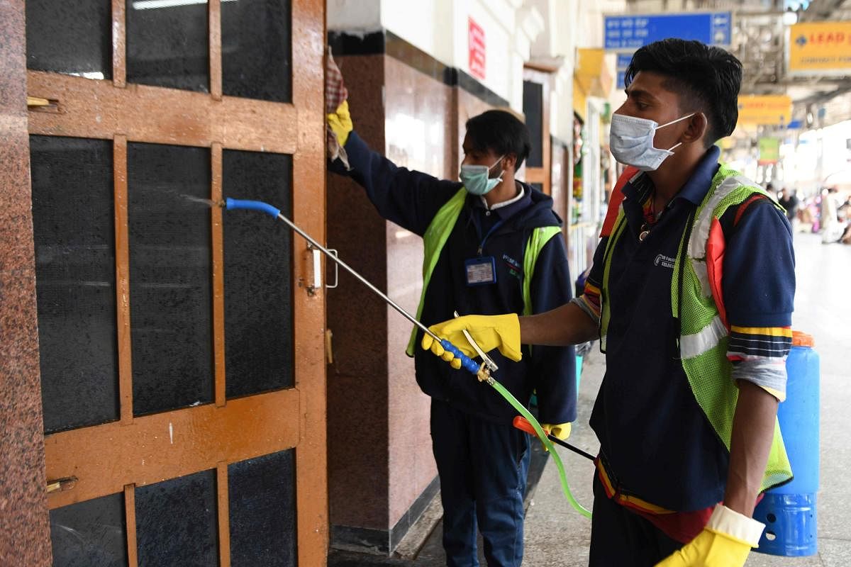 A railway workers sprays disinfectant on a door as a preventive measure against the spread of the COVID-19 coronavirus at a railway station in Amritsar on March 16, 2020. (AFP Photo)