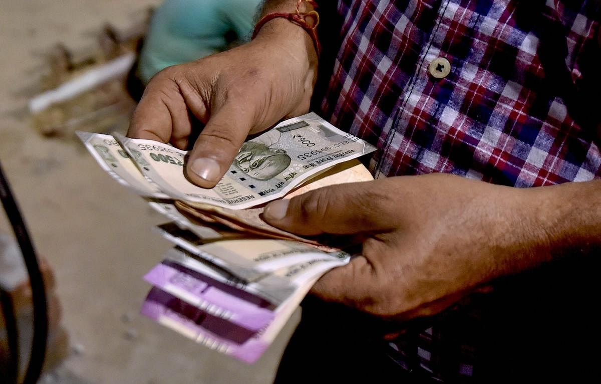 A customer counts Indian Rupee notes at a fuel station, in Kolkata. PTI Photo