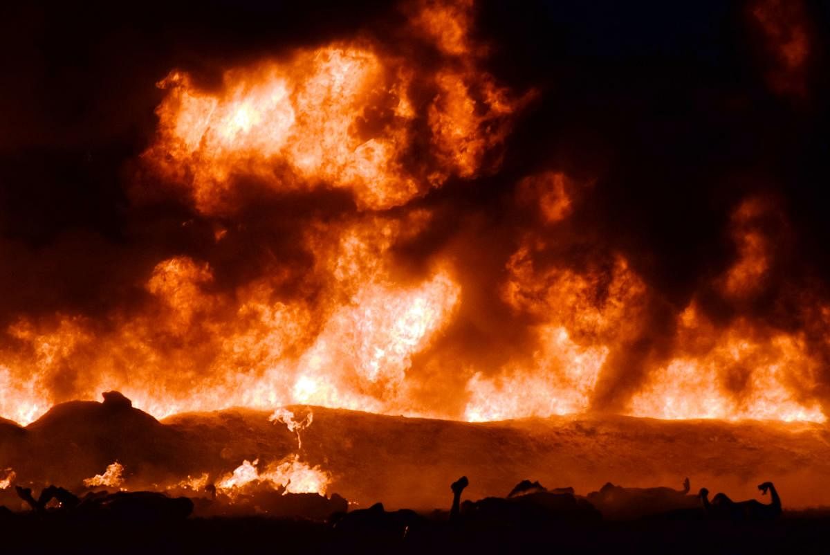 The fire is raging behind the bodies of burned victims at the scene of a massive blaze trigerred by a leaky pipeline in Tlahuelilpan, Hidalgo state, Mexico on January 18, 2019. - An explosion and fire has killed at least 66 people who were collecting fuel