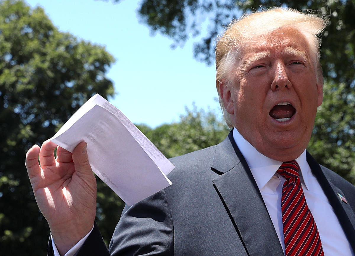 U.S. President Donald Trump holds up a copy of a deal with Mexico on immigration and trade as he speaks to the news media prior to departing for travel to Iowa from the White House in Washington, U.S., June 11, 2019. The document says the U.S.-Mexico migrant agreement reached last week includes a regional asylum plan and that Mexico agreed to examine its laws and potentially change them in order to implement the deal.  REUTERS/Leah Millis