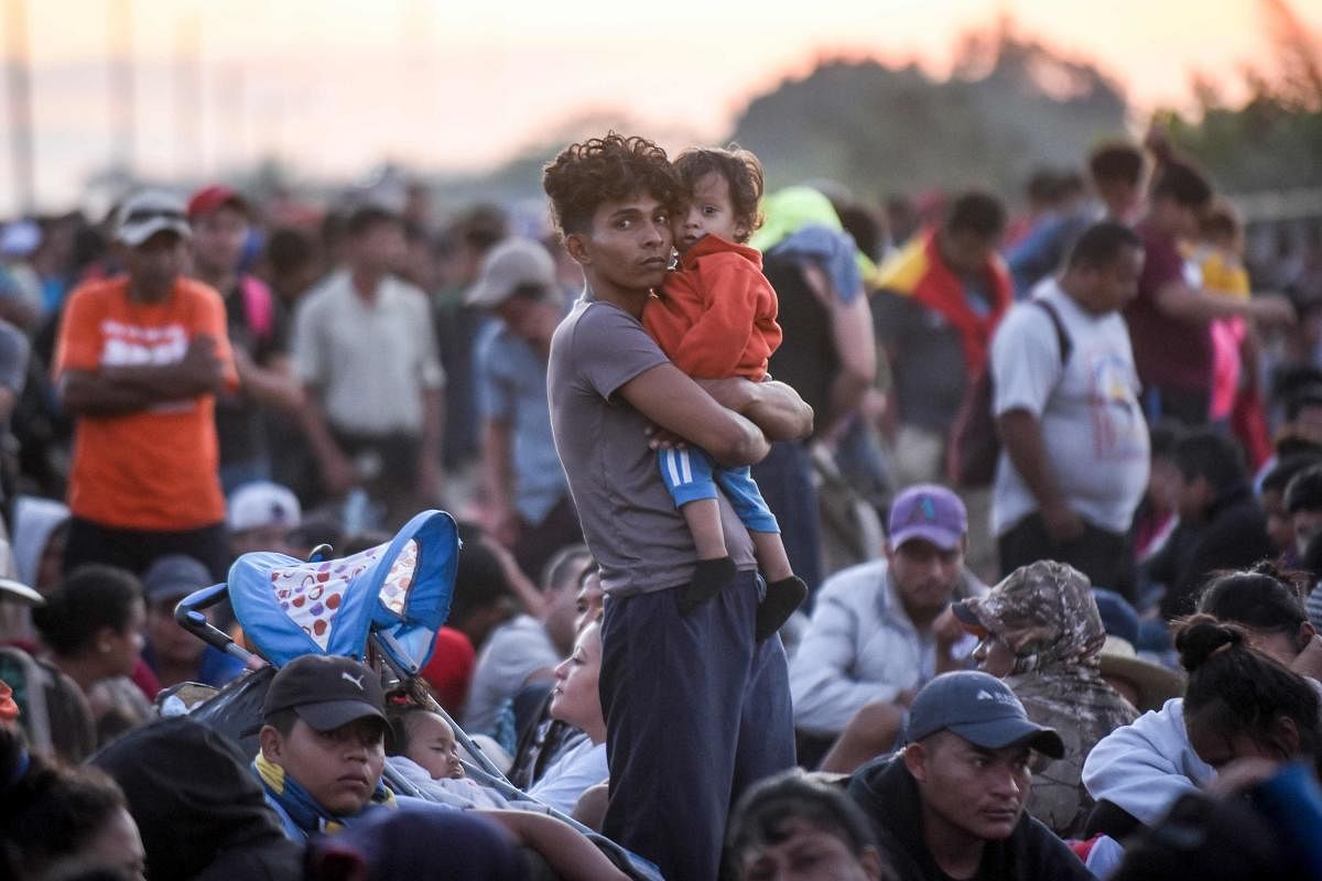 A Central American migrant and his baby travelling on caravan to the US, remain with a group of mostly Honduran migrants at the international bridge that connects Tecun Uman, Guatemala, with Ciudad Hidalgo, Mexico, on January 20, 2020. (AFP Photo)