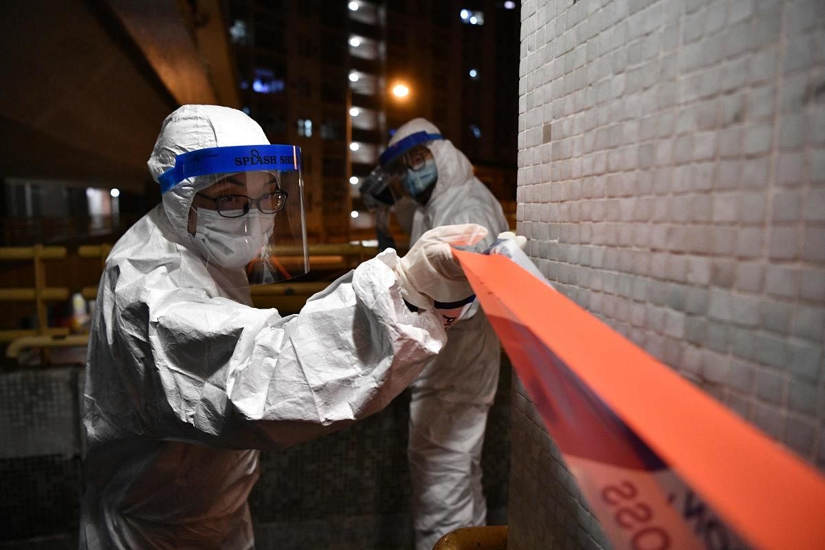 Police officers wearing protective suits set up a cordon in the grounds of a residential estate in Hong Kong. (AFP Photo)