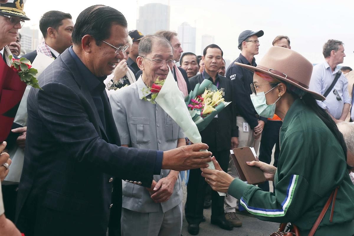 Cambodia's Prime Minister Hun Sen, left, gives a bouquet of flowers to a passenger who disembarked from the MS Westerdam, owned by Holland America Line, at the port of Sihanoukville, Cambodia, Friday, Feb. 14, 2020. Hundreds of cruise ship passengers long stranded at sea by virus fears cheered as they finally disembarked Friday and were welcomed to Cambodia. (AP/PTI Photo)