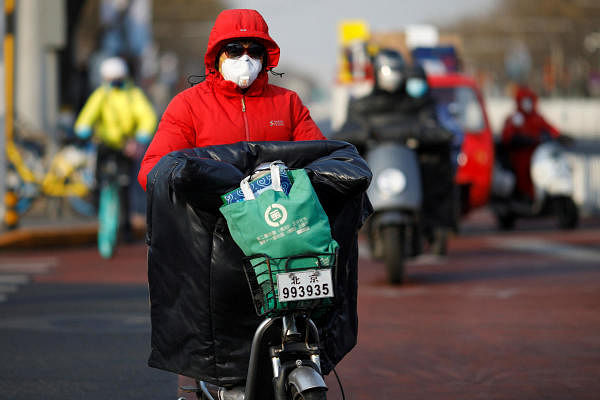 A woman wearing a face mask rides a scooter along a street, as the country is hit by an outbreak of the new coronavirus, in Beijing. (Reuters Photo)
