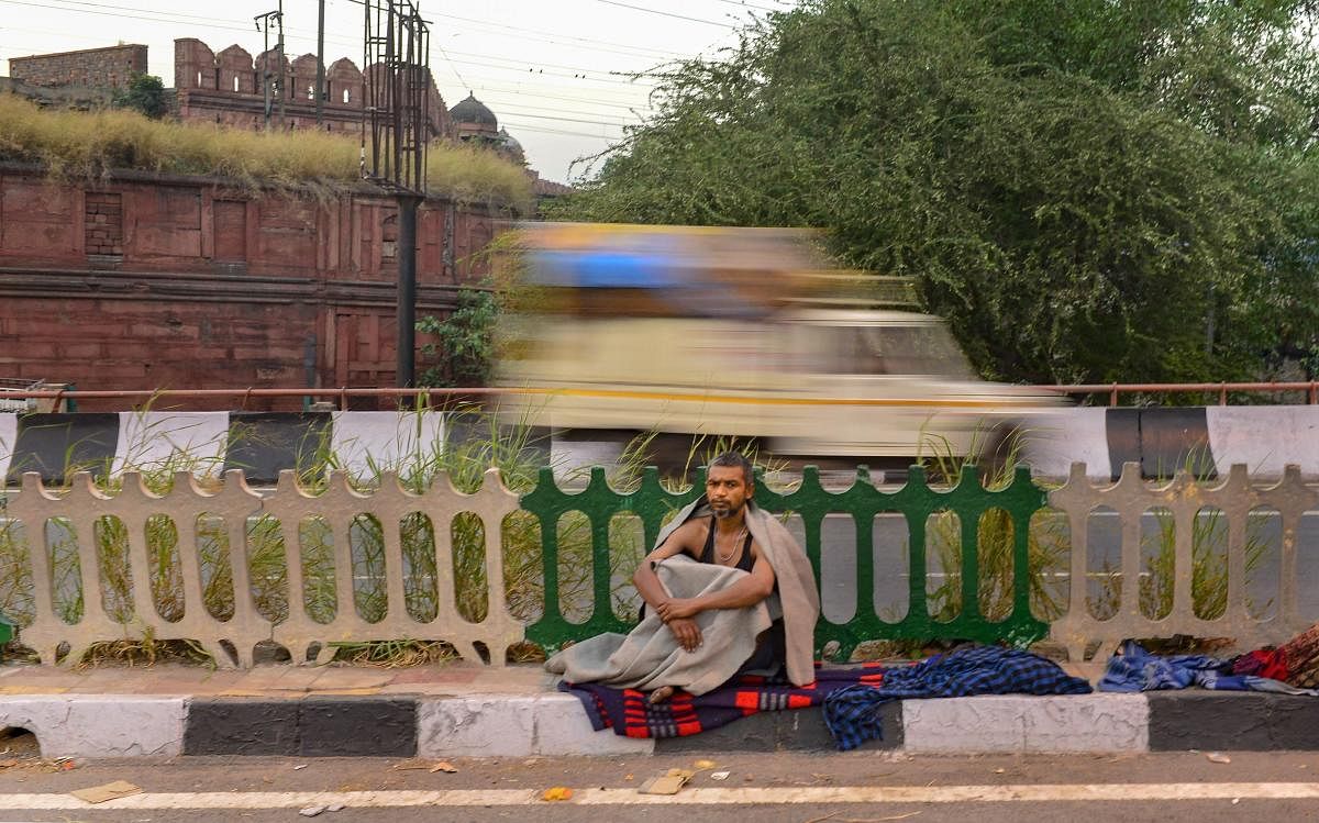 A homeless person sits at a pavement near Red Fort during the ongoing COVID-19 lockdown, in old Delhi. (PTI Photo)