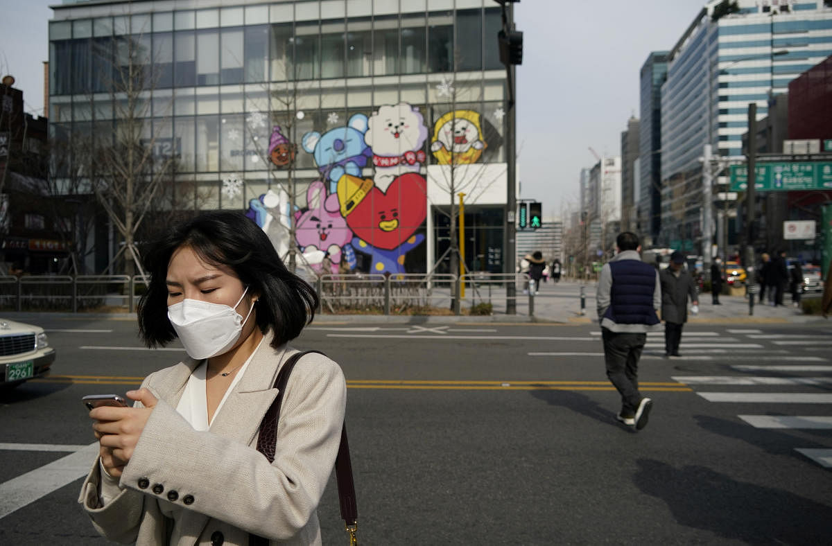 A woman wearing a mask to prevent the coronavirus uses her mobile phone at a shopping district in Seoul. Reuters