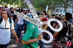 massive dissent:A protester carries a mock pair of scissors with the words cuts for politicians and bankers during a demonstration against education cuts in Madrid. AP