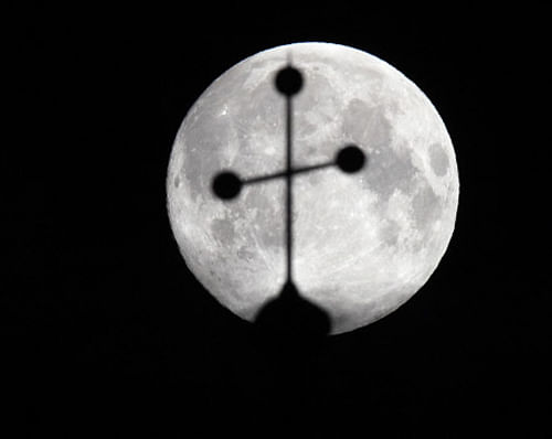 The super moon is pictured behind the cross of a church in Vienna June 23, 2013. The largest full moon of the year called the 'super moon' will light up the night sky this weekend. REUTERS.