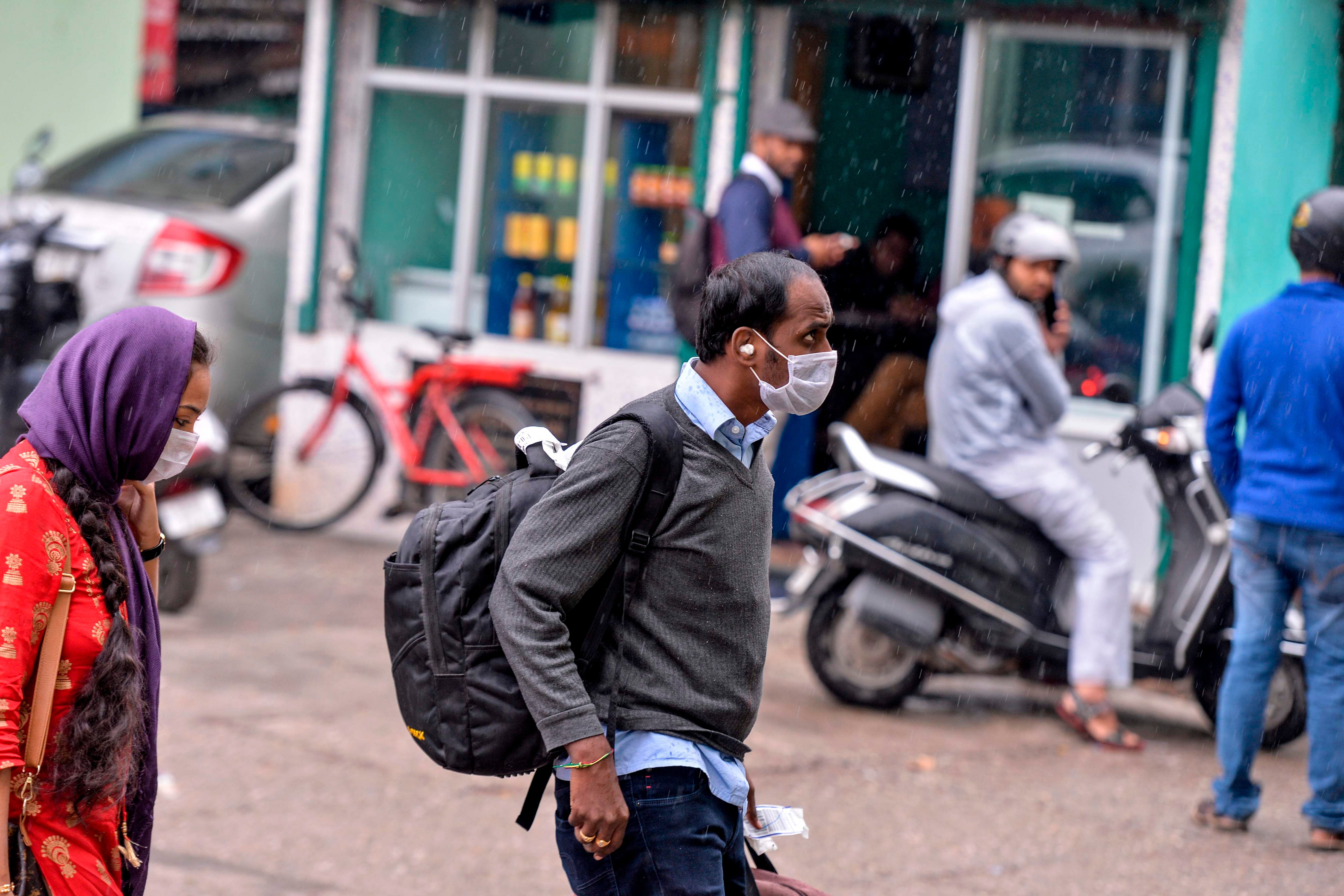 Travellers wear facemasks as they walk at the Sikkim Nationalised Transport (SNT) parking, following a ban put by the Sikkim government on all foreign tourists travelling from other countries to Sikkim state due to the COVID-19 coronavirus outbreak, in Siliguri. (AFP Photo)
