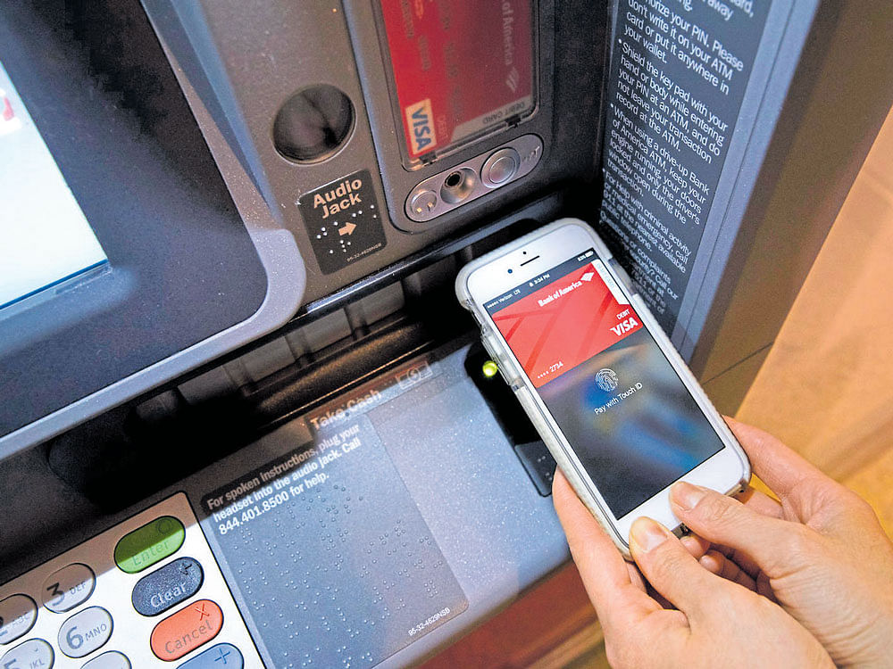 quick buck: A customer uses her smartphone and an ATM to do banking transactions, at the Bank of America Tower in Manhattan. Major banks are already testing teller machines that give you access with your phone, dispensing with the need for an ATM card. nyt