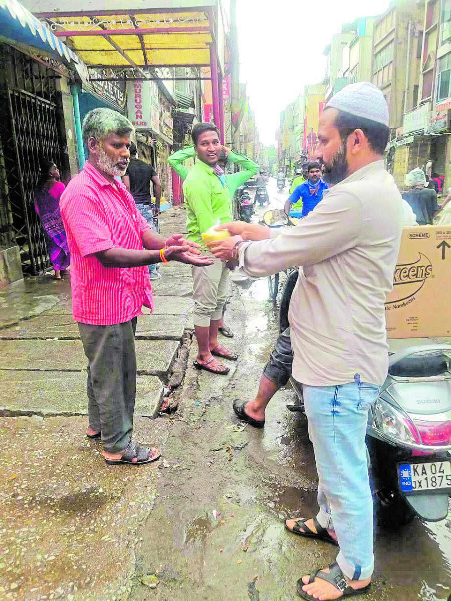 A volunteer distributes a food packet to the needy at K R Market in Bengaluru.