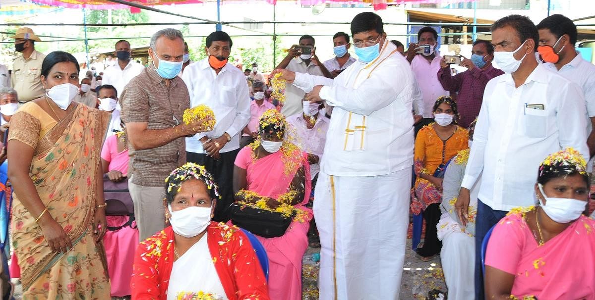Food and Civil Supplies Minister K Gopalaiah honours Covid-19 warrior Asha workers by showering flowers on them in Tumakuru on Saturday. DH Photo.