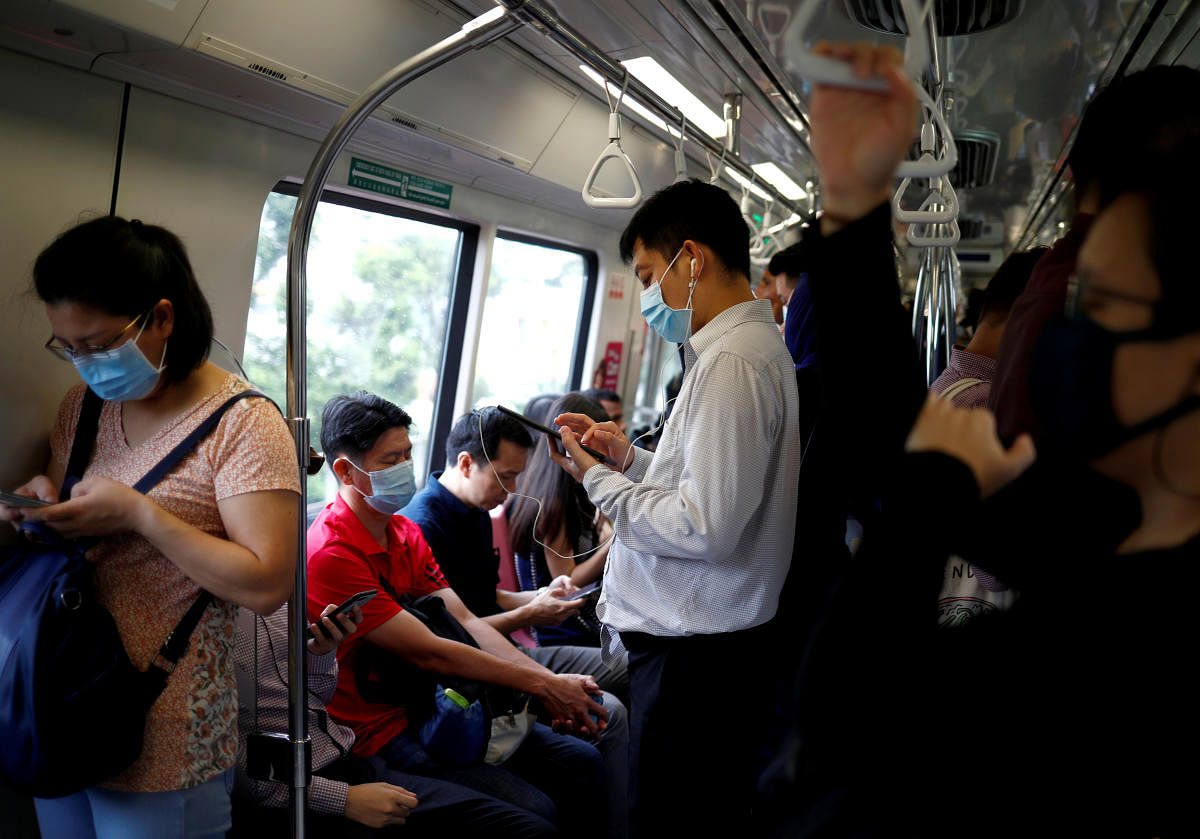  Commuters wearing masks in precaution of the coronavirus outbreak are pictured in a train during their morning commute in Singapore. Credit: Reuters File Photo