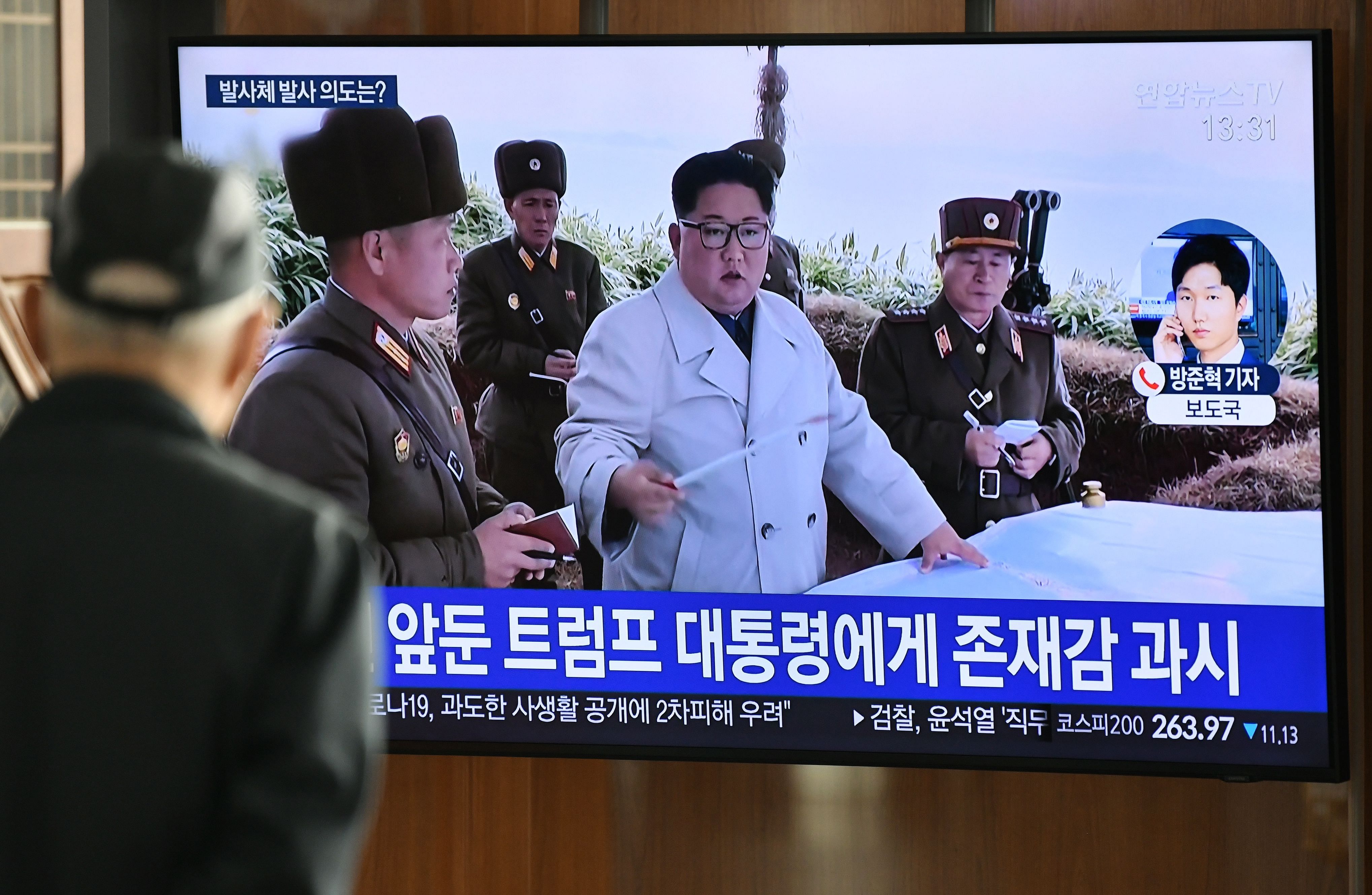 A man watches a television news broadcast showing file footage of North Korea's leader Kim Jong Un, at a railway station. (AFP Photo)
