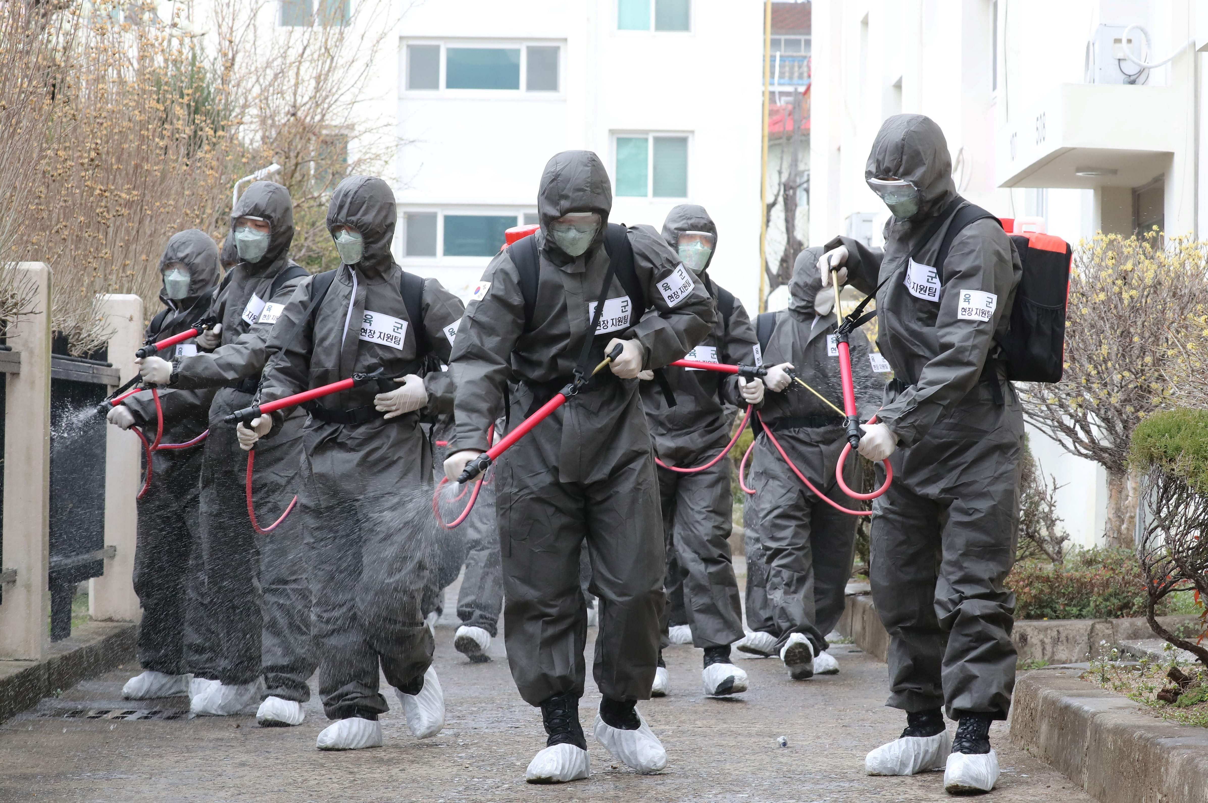 South Korean soldiers wearing protective gear spray disinfectant at a closed apartment complex after 46 residents were confirmed to have the COVID-19 coronavirus. (Credit: AFP Photo)
