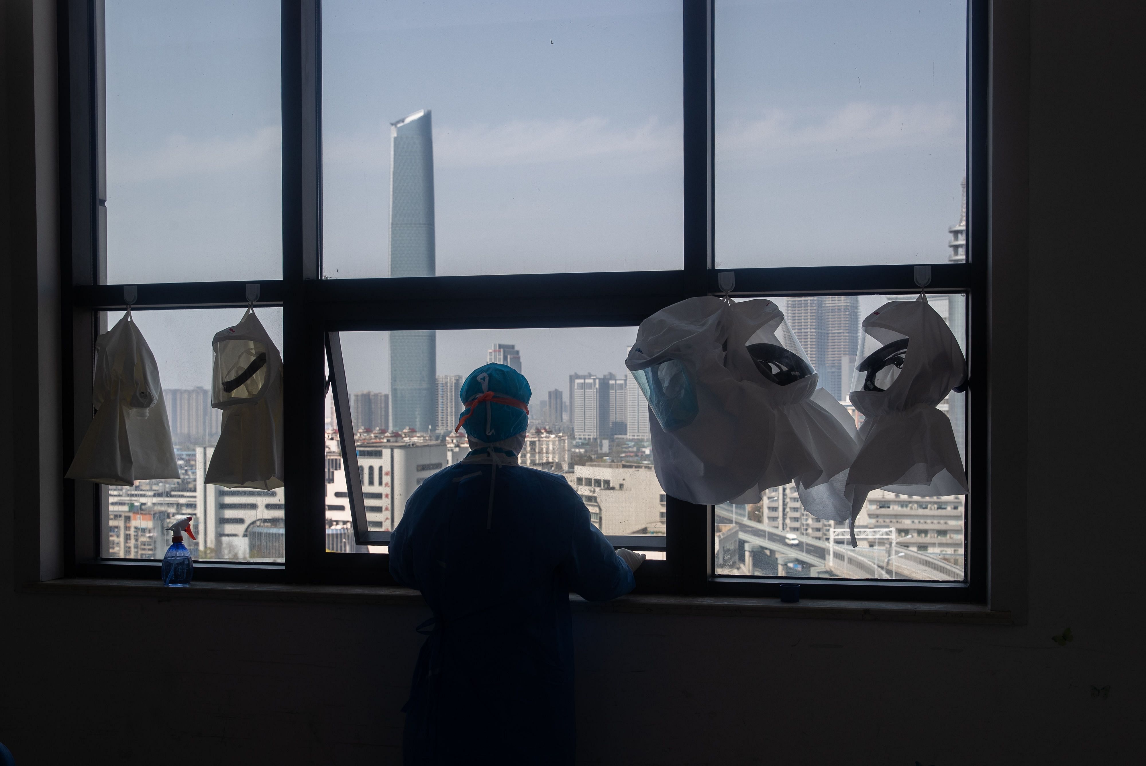 A medical worker looks out from the window of a changing room after treating COVID-19 coronavirus patients at a hospital in Wuhan. (Credit: AFP)