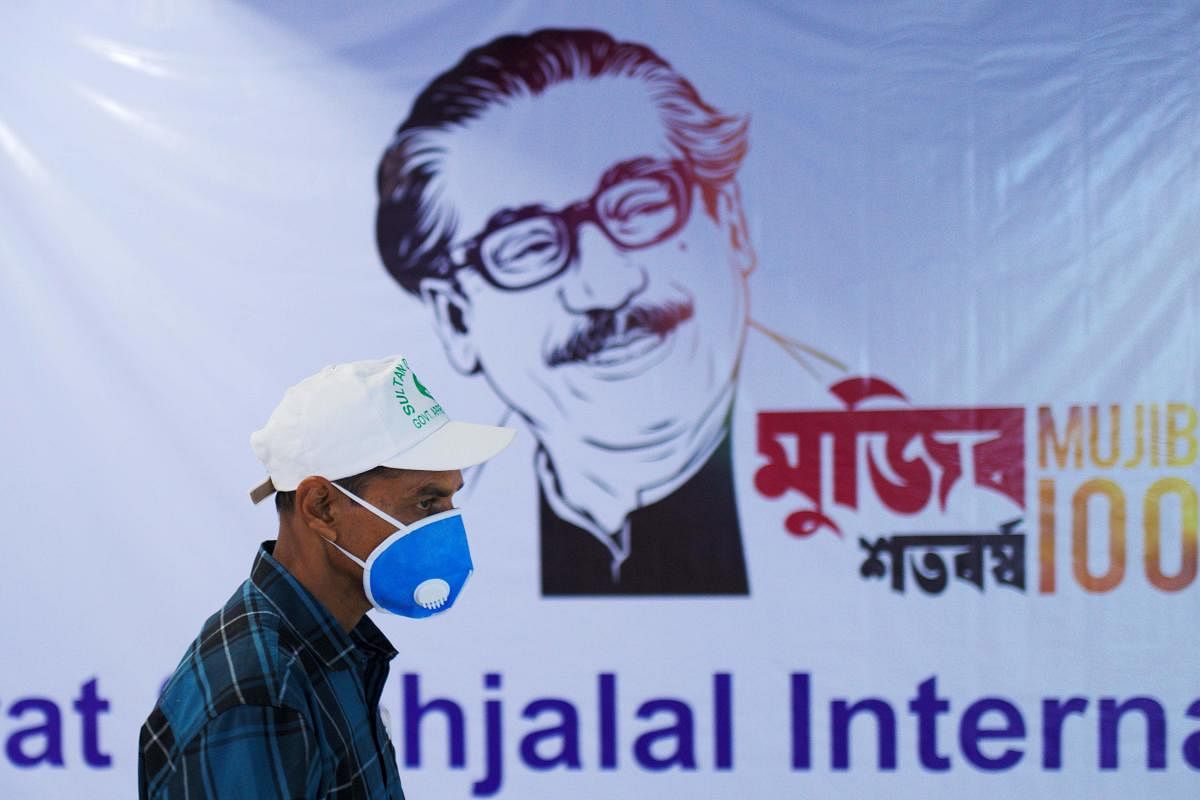 A man wearing a facemask as a preventive measure against the spread of the COVID-19 coronavirus outbreak, walks past a banner with a painting of Bangladesh’s founder Sheikh Mujibur Rahman at Hazrat Shahjalal International Airport in Dhaka. (AFP Photo)