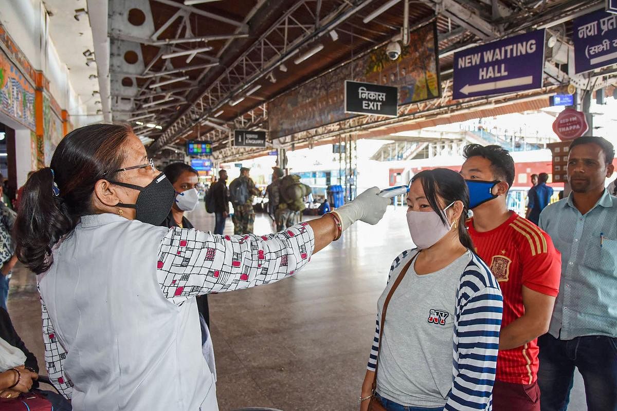 A health worker uses a thermal screening device on travellers in the wake of coronavirus pandemic in Patna (PTI Photo)