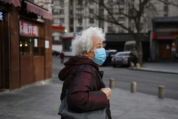 A woman wears a face mask as a preventive measure against the COVID-19 coronavirus as she walks on a street in Beijing on March 12, 2020. (AFP Photo)