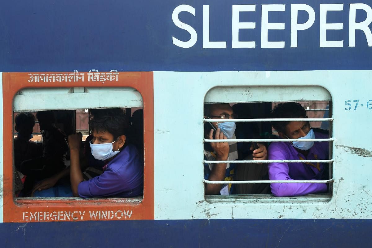 Migrant labours with their family members sit near a train window (AFP Photo)