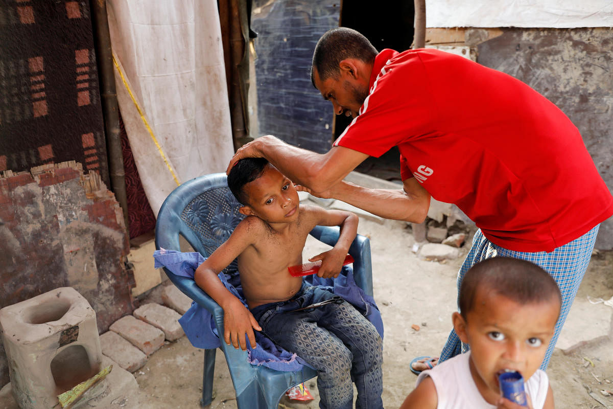 Rohingya refugee Md. Khaled, 25, gives a haircut to his son Masood, 8, at their house in a camp, during the fasting month of Ramadan and amid the outbreak of the coronavirus disease (COVID-19) in New Delhi, India April 30, 2020. Credit: Reuters Photo