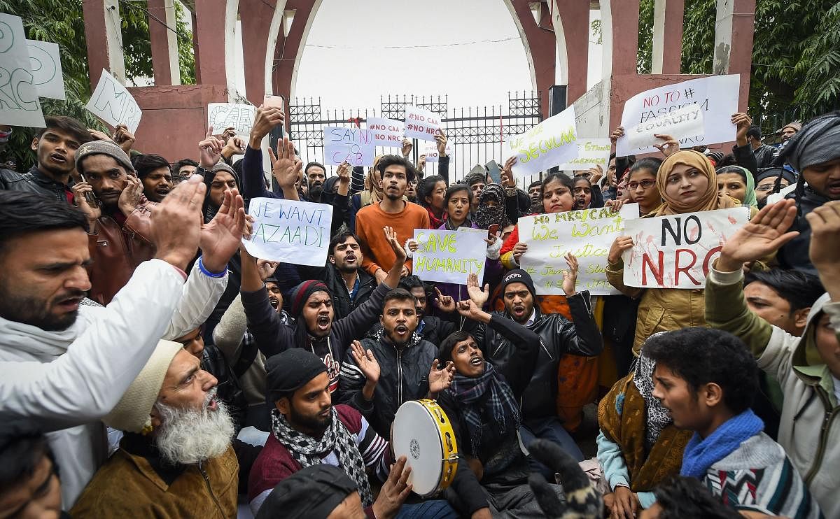 Students along with general public hold placards during a protest against the Citizenship Amendment Act (CAA), outside Jamia Millia Islamia University (PTI Photo)