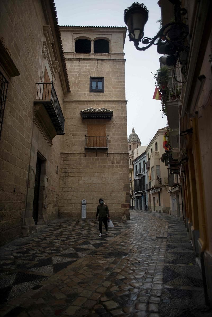 A lone man walks with a grocery bag in central Malaga, Spain. AFP